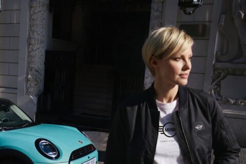 MINI amplia la propria offerta lifestyle con la nuova MINI Lifestyle Collection 2026, una gamma di prodotti pensati per portare lo stile e l’identità del marchio anche al di fuori dell’auto. La collezione accompagna la quotidianità in città così come i momenti di viaggio e di tempo libero. Occhiali da sole, borse a tracolla e shopper sono pensati per gli spostamenti quotidiani, mentre zaini e borse porta computer offrono soluzioni funzionali per l’ufficio, insieme a una tazza termica. Per i viaggi e le occasioni in cui serve maggiore capacità, la gamma comprende borsoni e trolley. Ombrelli e felpe con cappuccio completano invece l’offerta per affrontare anche le giornate meno favorevoli. Una collezione ispirata all’identità MINI La nuova proposta nasce con l’obiettivo di mantenere riconoscibile il carattere MINI attraverso prodotti destinati alla vita di tutti i giorni. «Con la nuova MINI Lifestyle Collection volevamo cogliere lo spirito del tempo e offrire diverse possibilità di stile, rimanendo fedeli all’identità inconfondibile di MINI», spiega Peter Zamljak, Head of MINI Lifestyle and Licences. Tra i prodotti preferiti da Zamljak c’è anche la tazza da caffè, proposta nello stesso colore della sua Cooper: un dettaglio pensato per portare lo stile MINI nella quotidianità fin dall’inizio della giornata. Colori ispirati alla gamma MINI La palette cromatica della collezione prende ispirazione da alcune delle tinte di carrozzeria più apprezzate dell’attuale gamma MINI. Ai colori essenziali Black e White si aggiungono le tonalità stagionali Ocean Wave Green, Smokey Green e Rebel Red. Una scelta cromatica che permette di combinare gli elementi più discreti della collezione con proposte dai colori più decisi. Abbigliamento per uomo e donna La linea di abbigliamento comprende T-shirt, cappellini, polo, felpe con cappuccio e giacche, rivolti sia al pubblico maschile sia a quello femminile. La collezione punta su vestibilità confortevoli e materiali di qualità, arricchiti dai dettagli di design che caratterizzano il marchio MINI. Borse e valigie per città e viaggi Ampia anche la proposta dedicata a borse e valigie. La gamma comprende borse a tracolla, shopper, zaini roll-top e borse porta computer, oltre a borsoni e trolley. Materiali resistenti, scomparti funzionali e una buona capacità di carico sono gli elementi su cui si basa una linea pensata per accompagnare sia gli spostamenti quotidiani sia i viaggi. Gli accessori per la vita di tutti i giorni La collezione comprende anche una selezione di accessori destinati all